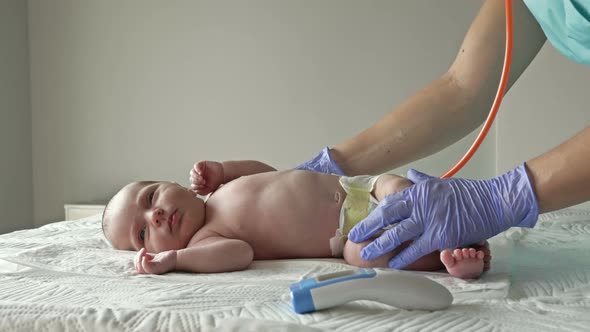 Neonatologist in Latex Gloves Examines a Newborn Baby with a Stethoscope