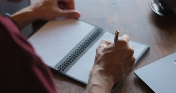 Man's Hands Making Important Notes in Paper Diary with Pen