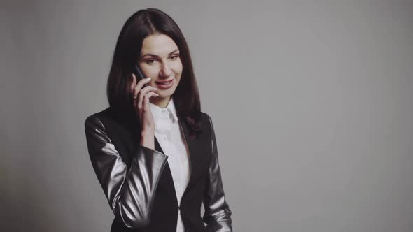 Woman talking on the phone. Young stylish woman talking on phone and posing in the studio