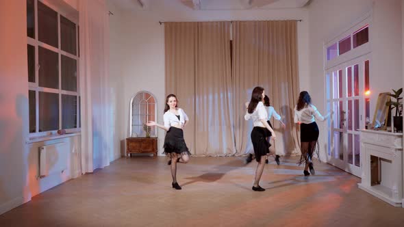 Four Girls in Black Skirts and White Shirts are Dancing Indoors