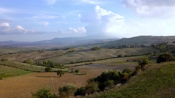 Italian villas on farm fields in the Tuscan countryside, Aerial approach reveal shot