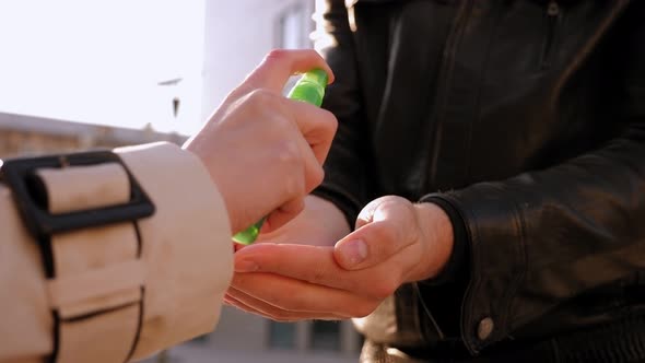 Closeup of Female and Male in Medical Mask Cleaning Her Hands with Sanitizer