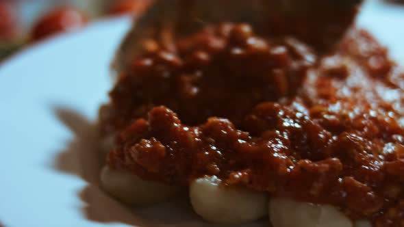 Gnocci with Tomato Sauce Being Sprinkled with Parmesan