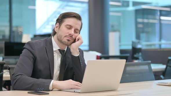 Tired Businessman Taking Nap While Sitting in Office with Laptop