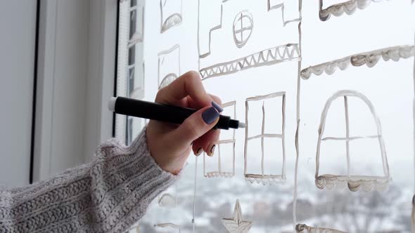 Female Hand Draws Christmas Holidays Decoration on Window Glass