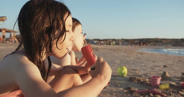Three kids eating watermelons at the beach