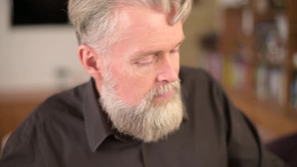 close-up of the face of a solid bearded gray-haired man who plays the piano