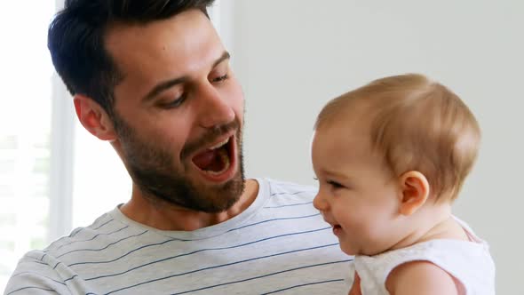 Father playing with his baby girl in bedroom