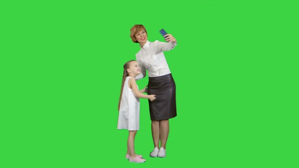 Smiling Mother and Daughter Bonding Together To Take a Selfie on a Green Screen, Chroma Key