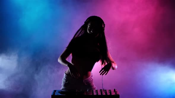 Girl DJ with Headphones Her Hair Is Developing the Wind. Slow Motion. Silhouette