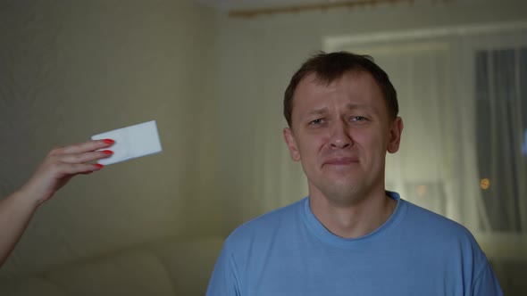 A man cries, stands right in front of the camera, takes an outstretched paper towe