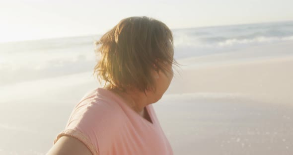 Portrait of smiling senior african american woman walking on sunny beach