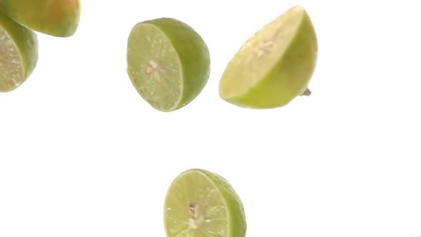 Halves of Delicious Limes are Falling Diagonally on the White Background