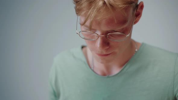 Closeup Shot of Young Man Studying and Stressing Reading in Empty Grey Room