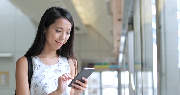 Woman looking at smart phone on train platform