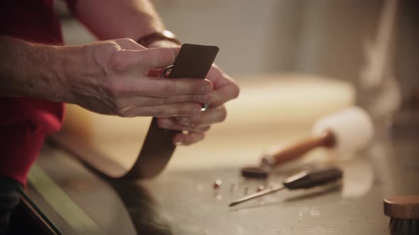 A Man Attaches a Clasp to a New Leather Strap