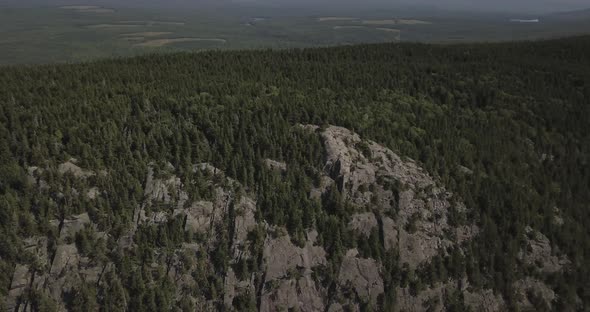 Aerial Drone Shot Orbiting Around Rocky Cliff Edge Of Mountain Forest