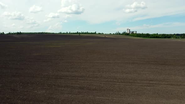 Aerial Drone View Flight Over Huge Plowed Field and Blue Sky