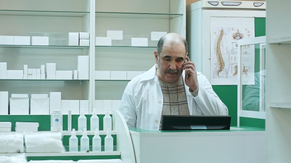 Pharmacist talk with client using mobile phone in pharmacy