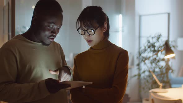 Multiethnic Coworkers Using Tablet and Speaking in Office at Night