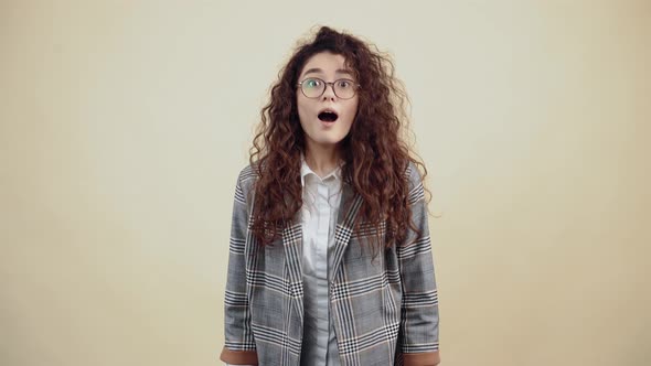 Shocked Excited Young Woman with Her Hands in Her Hair Says Wow Looking Curiously at the Camera