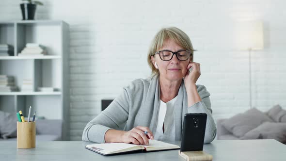 Pretty Woman With Long Hair And Glasses. Communication Remotely. She Is In Headphones And Talking