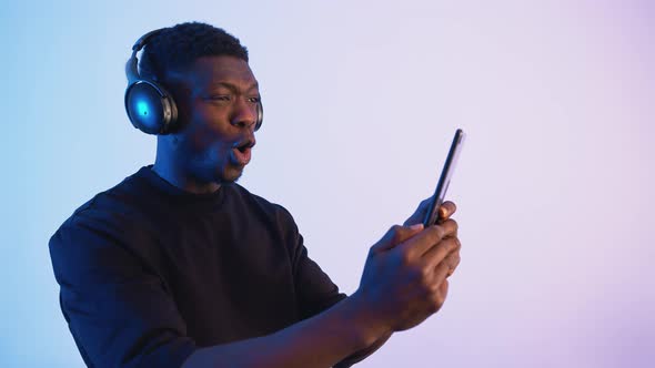 African American Man Wearing Headphones Holding a Phone in His Hand