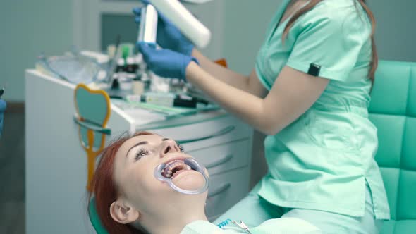 Young Woman Sits in Chair at Reception at Dentist