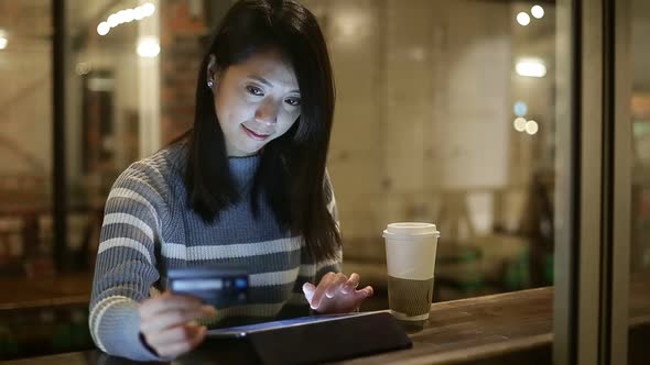 Woman using tablet pc at coffee shop at night