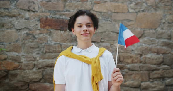 Portrait of French Teenager Holding National Flag of France Smiling Outdoors