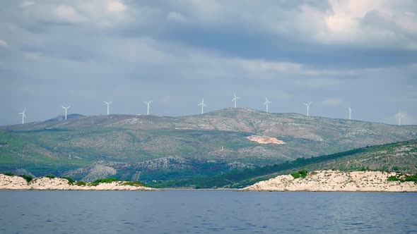 Wind Turbines Spinning On The Coastal Mountain In Croatia - View From Floating Boat In The Sea - wid