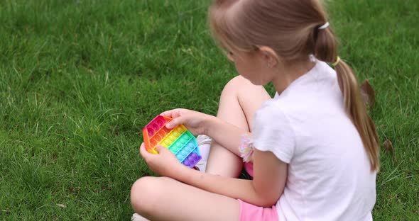 Child Playing with Rainbow Pop It Fidget Toy Outdoor