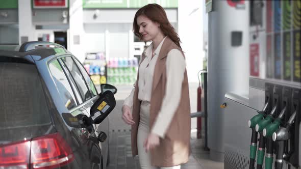 Young Female Customer Fueling Car with Gasoline at Gas Station, Girl Inserts Fuel Nozzle Is Getting