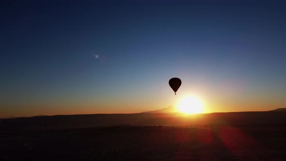 Aerial Landscape of Summer Sunset Over Mountain Range and Rocky Valley with Hot Air Balloon in Sky