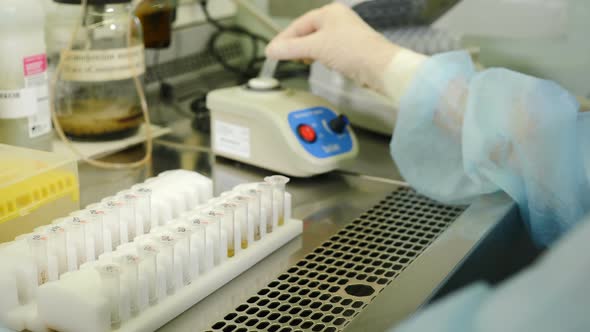 Scientist Working in Sterile Genetics Laboratory with Pipette in Medical Dressing Gown