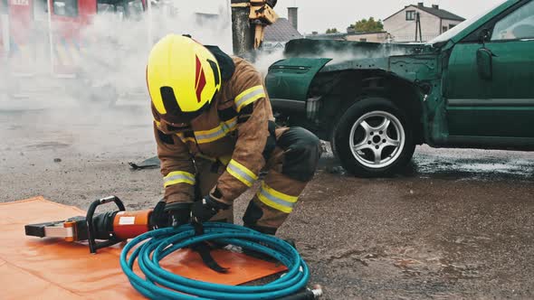 Firefighters Preparing the Hose Wor Hidraulic Cutter on the Car Crash Scene