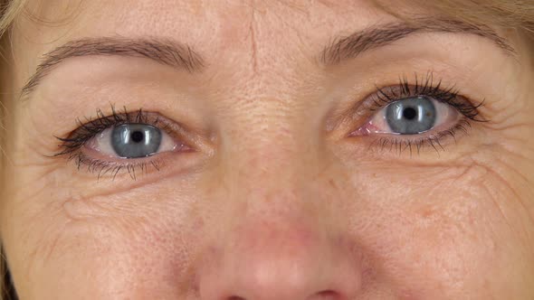 Woman Blue Eyes with Wrinkles Looking Straight and Smiling, Close Up