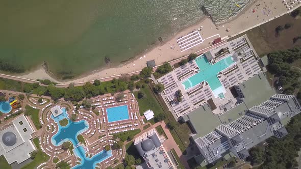 Top down aerial view of hotels on ocean shore with swimming pools with blue water and beach