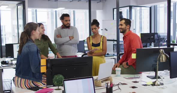 Diverse group of work colleagues looking at computer monitor and talking