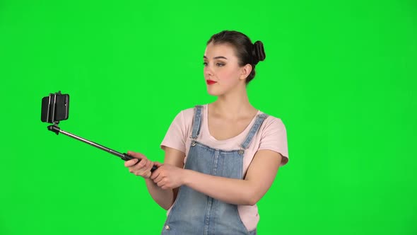 Girl Makes Selfie on Mobile Phone Using Selfie Stick on Green Screen