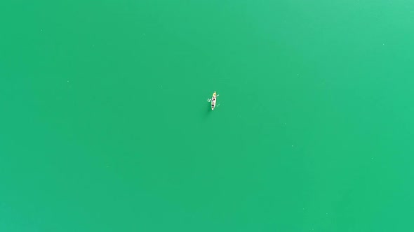A birdseye view of 2 people in a Kayak on a green lake in Khao Sok, Surat Thani, Thailand.