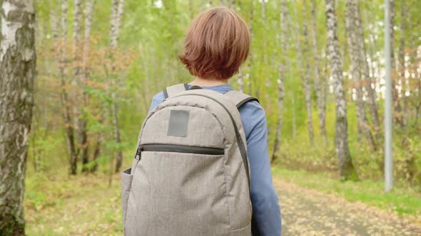 Teenager Boy with Backpack Walking on Path in Autumn Park