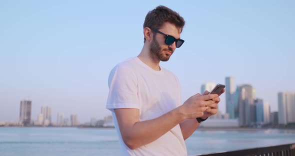 The Man Dials the Number on the Phone and Talks on the Background of the Panorama of Dubai. Hand