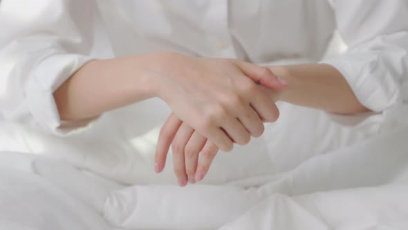 Close up of woman hand holding and applying moisturiser, Body lotion in bedroom.