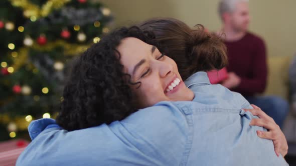 Happy diverse male and female friends hugging at christmas time