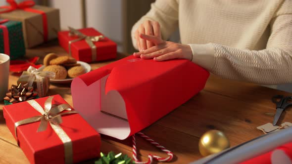 Woman Wrapping Christmas Gift Into Paper at Home