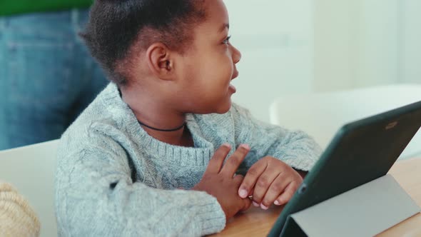 Positive African little girl watching something at the tablet