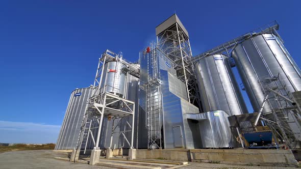 Modern plant for agribusiness. Silver grain elevators on blue sky background.