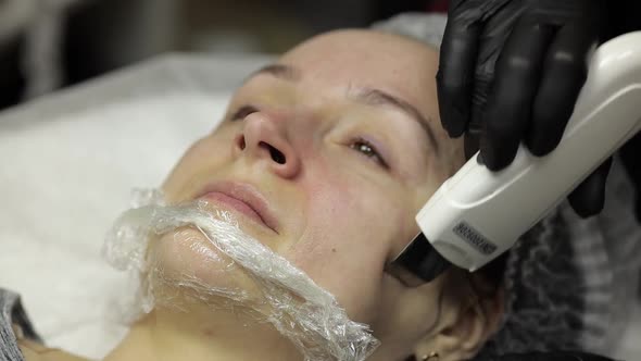 Cosmetologist Make Ultrasonic Face Cleaning on Woman Face in Beauty Clinic Salon
