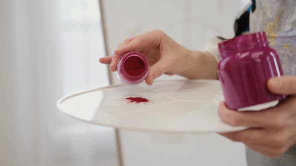 The Artist's Hand Pours a Colored Patch on a Palette with Oil Paint